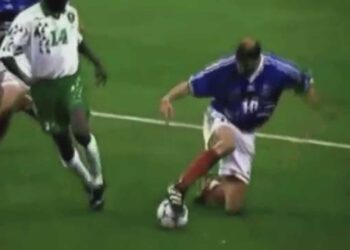 Jugador de fútbol en acción disputando el balón en césped durante un partido