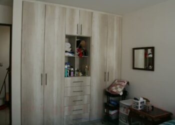 Armario empotrado de madera clara en dormitorio ordenado con estantes abiertos y espejo, La casa de María en Sevilla: el refugio de los famosos y su encanto