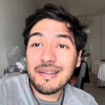 Hombre joven con barba y brackets en primer plano dentro de una habitación doble de hotel