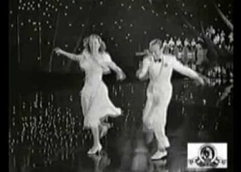 Parejas de baile icónicas que deslumbran en la pista de baile: dúo vintage en traje y vestido ejecutando pasos de salón en un escenario