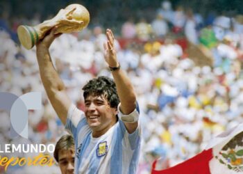 Futbolista celebrando con el trofeo mundial ante una multitud en un estadio