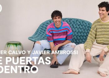 La impresionante casa de los Javis: lujo y estilo en Madrid, salón contemporáneo con dos hombres sonrientes, sofá trenzado turquesa y elementos cerámicos decorativos