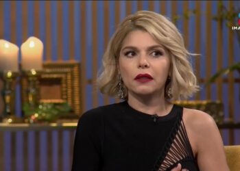 Mujer rubia con peinado corto y vestido negro en set televisivo, mirada pensativa; Descubre quién es el esposo actual de Itatí Cantoral y su historia