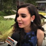 Joven siendo entrevistada al aire libre con micrófono y logo del canal