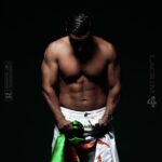 Los romances más icónicos de Penélope Cruz que no te puedes perder en una fotografía de torso masculino musculoso sobre fondo oscuro sujetando una tela verde y blanca.