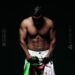 Los romances más icónicos de Penélope Cruz que no te puedes perder en una fotografía de torso masculino musculoso sobre fondo oscuro sujetando una tela verde y blanca.