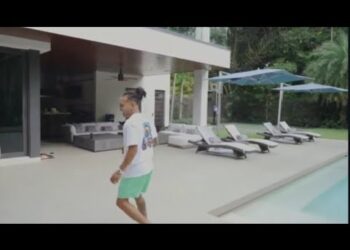 Mansión en Miami con piscina y terraza moderna y una persona caminando junto al patio