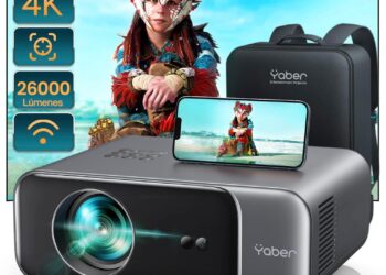 Proyector Yaber en primer plano con lente iluminada, teléfono mostrando reproducción de vídeo y funda de transporte a un lado 【Auto Focus/Keystone】Proyector WiFi Bluetooth 4K Soporte,26000 Lúmenes YABER Proyector WiFi6 Full HD 1080P Nativo Proyector Portátil Cine en Casa/Exterior para Movil/iOS/Android/TV Stick/PS5 HDMI USB