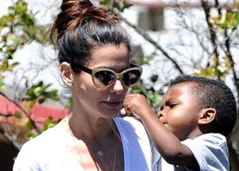 Mujer con gafas de sol y niño pequeño en un gesto cariñoso, retrato al aire libre que transmite ternura y cuidado parental.