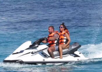 Pareja en moto de agua con chalecos salvavidas sobre mar azul turquesa