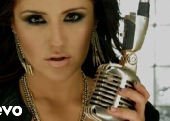 Primer plano de una cantante con maquillaje ahumado sujetando un micrófono vintage 9GN4Lanv f4.