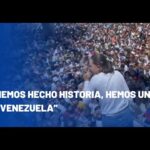 Mujer en escenario hablando ante una multitud con logo de noticias y lema visible, Esposo de María Corina Machado: historia y secretos revelados