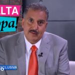 Presentador en el set de Suelta la Sopa con logo de Telemundo, traje gris y corbata naranja