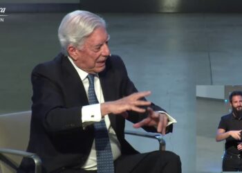 Hombre mayor con traje y corbata gesticulando mientras habla en un escenario, acompañado por un intérprete de lengua de señas y el logotipo de Fundación Telefónica.