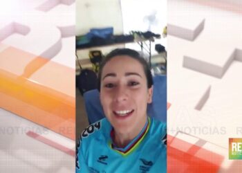 Mujer sonriente con camiseta deportiva azul y cuello multicolor en un interior con equipo y maletas, La familia de Egan Bernal: el apoyo incondicional detrás del campeón