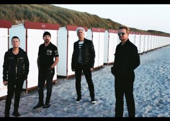 Cuatro músicos de pie en la playa junto a filas de casetas blancas y techos rojos, La sorprendente fortuna de Paul McCartney: ¿cuánto realmente tiene?