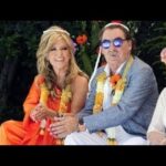 Quién es Charly, el marido de Lydia Lozano y su historia oculta: pareja sentada con guirnaldas florales en un ambiente festivo, ella con vestido naranja y él con chaqueta clara y gafas