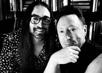 Dos hombres retratados en blanco y negro frente a una estantería, imagen evocadora para Hijos de John Lennon: Descubre su legado y vida actual.