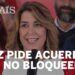Mujer sonriente hablando frente a un micrófono en un acto público con un titular editorial visible sobre acuerdos que no bloqueen.