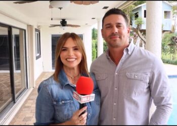 Mujer presentadora sonriente con micrófono rojo junto a un hombre en una terraza junto a una piscina; texto promocional: Descubre quién es el esposo de Rashel Díaz y su historia de amor