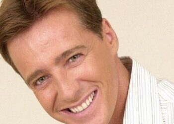 Retrato cercano de hombre adulto sonriente con camisa clara y mirada amable