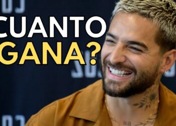 El impresionante patrimonio de un famoso artista: secretos de su fortuna, primer plano sonriente con tatuajes y texto 'CUANTO GANA?'