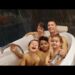 Padre sonriente con cuatro niños en una bañera, momento familiar íntimo y alegre.