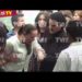 Persona atendida por otra en una multitud durante una transmisión televisiva en vivo