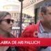 Personas caminando por la calle con un rótulo televisivo que dice Ari Paluch: Descubre dónde trabaja y sus nuevos proyectos en radio.