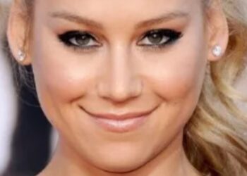 Primer plano de una mujer sonriente con maquillaje marcado y pendientes brillantes, La familia de Enrique Iglesias: amor, secretos y momentos únicos