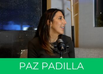 Mujer en perfil hablando frente a un micrófono en un set interior junto a una ventana.