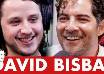 Dos hombres sonrientes con auriculares y micrófonos en un estudio de podcast OHJ1mEDduco