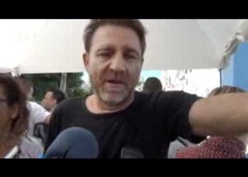 Hombre hablando frente a micrófonos en una entrevista al aire libre; ¿Qué fue de Verano Azul? Descubre la vida de sus protagonistas