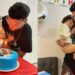 Hombre con su hijo soplando velas sobre una tarta azul decorada con coches de juguete