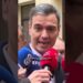 Hombre hablando frente a varios micrófonos de medios de prensa durante una declaración pública