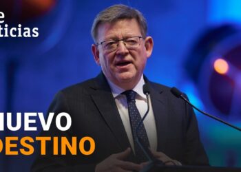 Hombre con gafas y traje hablando en un atril bajo luces azules, El sorprendente sueldo de [nombre omitido]: ¿cuánto cobra realmente?