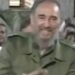 Hombre mayor con barba y chaqueta militar verde sonriendo en un evento público