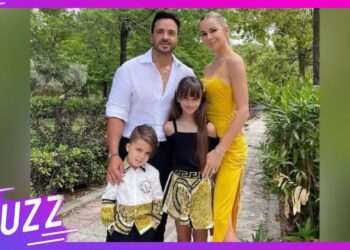 Familia posando al aire libre: dos adultos y dos niños vestidos de forma elegante en un entorno ajardinado.