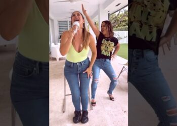 Dos mujeres sonrientes cantando en un patio con micrófono y ropa casual, descubre su nuevo trabajo y emocionantes proyectos