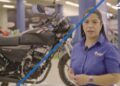 Descubre de dónde es AKT Motos y su impacto en Colombia mientras una representante presenta una motocicleta en un showroom.