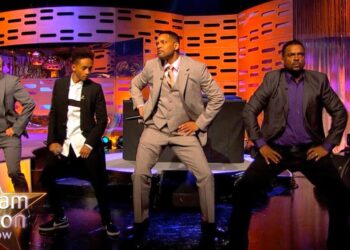 Cuatro hombres vestidos con trajes realizan una coreografía en el plató de un programa nocturno; Descubre la sorprendente fortuna de Alfonso Ribeiro: lo que ha ganado tras años en la televisión y el impacto de su carrera en tu vida