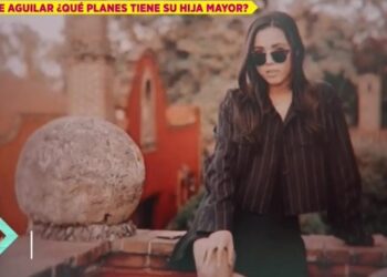 Mujer joven con gafas de sol posando sobre un muro de piedra en un entorno arquitectónico tradicional