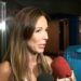 Mujer con cabello largo habla ante micrófonos rojos mientras un hombre la escucha asqR8jahe3s