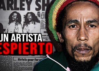 Primer plano de un músico con gorro rastafari tricolor, barba y mirada intensa frente a un fondo de recortes de periódicos y el titular 'UN ARTISTA DESPIERTO'.