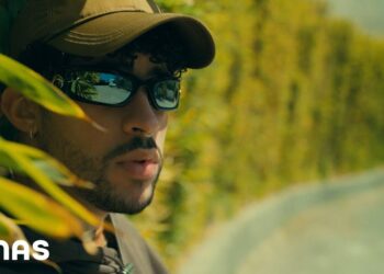 Hombre con gorra y gafas de sol entre hojas, estética urbana bad bunny 1.