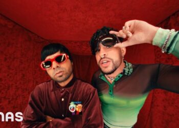 Dos músicos con gafas de sol y ropa llamativa en un set rojo, De dónde es Bad Bunny: descubre sus raíces puertorriqueñas.