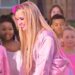 Artista rubia con chaqueta rosa sonriendo y rodeada de niños en un evento al aire libre — ¿Qué fue de Aqua? Descubre la historia detrás de Barbie Girl.