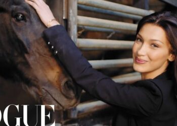 Mujer joven sonriente acariciando la cabeza de un caballo en un establo, retrato íntimo con estética editorial
