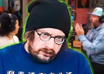 No podrás creer por qué todos están obsesionados con este nuevo drama de 6 episodios tras su increíble primer capítulo: primer plano de un presentador con gorro y gafas en un estudio de podcast, con dos colaboradores con auriculares al fondo.