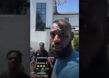 Hombre con barba en primer plano frente a una canasta de baloncesto y dos jóvenes detrás, bronny bryce